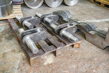 After manufacturing, the industrial crankshaft rests on the rack in the warehouse.