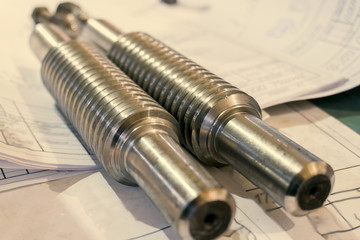 The screw shaft after manufacturing on a lathe lies on the technical drawing.