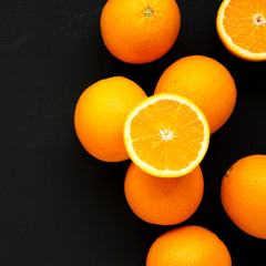 Ripe organic oranges on a black surface, top view. Flat lay, overhead, from above. Copy space.