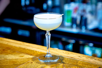 Yellow cocktail with foam on top of the glass is on the table