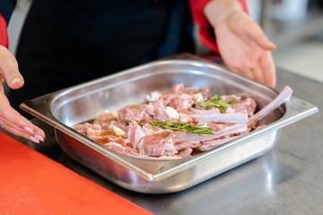 Chef holding a metal container with lamb steak