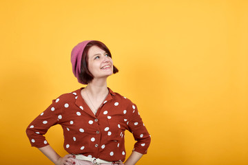 Gorgeous caucasian brunette young lady wearing pretty red shirt with polka dot staying over isolation yellow background posing with arms at hip and laughing