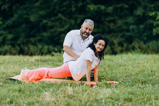 Middle age woman doing yoga. Man help for woman with exercise.- - Image