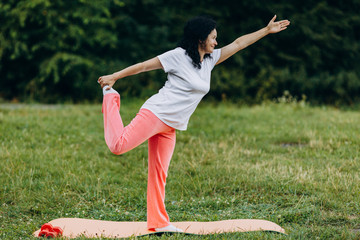 Middle age woman doing yoga pose holding her leg outdoor.- Concept sport - Image