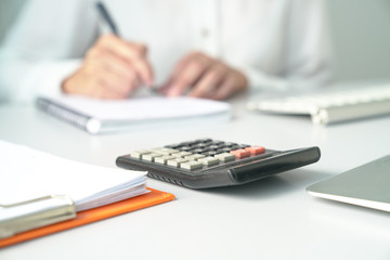 Office table view with out of focus on Accountant, focus on calculator