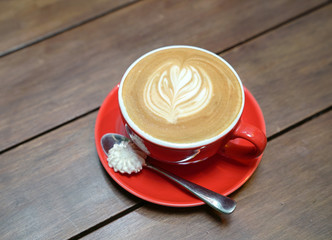 Flat white coffee with heart pattern in a red cup