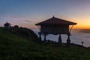 Typical granary (horreo) and the chapel of La Regalina in Cadavedo, Asturias, Spain