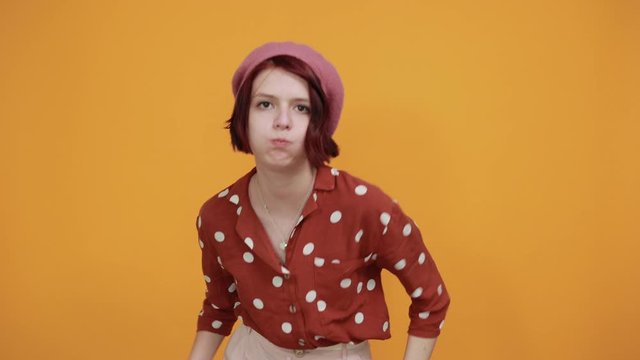 Young funny beautiful caucasian woman wearing nice pink hat and red fashion shirt puffing cheeks with funny face. Mouth inflated with air, show tongue, crazy expression.