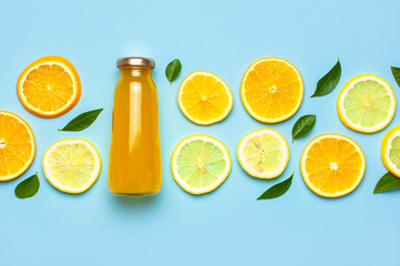 Flat lay composition with glass bottles of juice or fresh, slices of fresh lemon and orange, green...