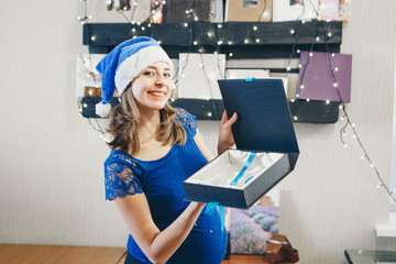 woman in Christmas blue hats offer box. The concept of celebrating the new year, costumes of Santa Claus and snow maiden, gifts