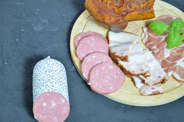 Assortment of salami and snacks. Sausage Fouet, sausages, salami, paperoni. On a black and wooden background. Top view. Free space for your text.