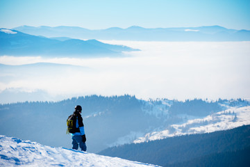 Snowboarder Standing on the Hill and Enjoying the View of Mountains at Sunny Day. Snowboarding and...