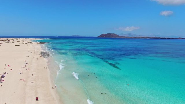 High angle aerial drone footage of Corralejo National Park beach located in the northeast corner of the island of Fuerteventura, Canary Islands, Spain. Islands of Lobos and Lanzarote in background.