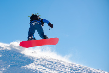 Snowboarder Riding Red Snowboard in Mountains at Sunny Day. Snowboarding and Winter Sports
