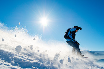 Snowboarder Riding Snowboard in Mountains at Sunny Day. Snowboarding and Winter Sports