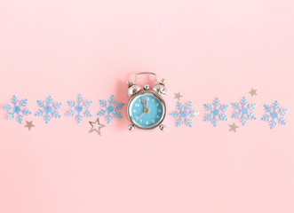 Christmas background. Retro alarm clock blue, blue snowflakes on pastel pink background top view. flat lay