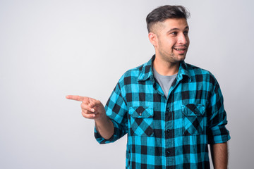 Portrait of happy young Persian hipster man pointing finger and looking away