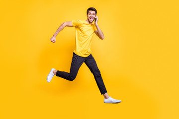 Fototapeta na wymiar Full body photo of handsome guy jumping high talking telephone rushing romantic date see girlfriend wear casual t-shirt trousers isolated yellow color background