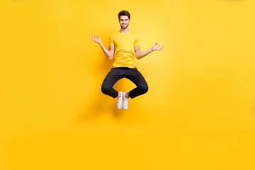 Fotobehang Full body photo of handsome guy jumping high lotus position morning yoga training relaxing fingers together wear casual t-shirt black trousers isolated yellow color background © deagreez