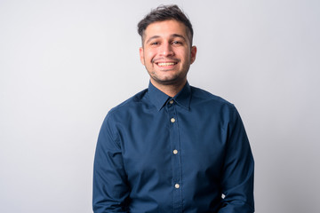 Portrait of happy young handsome Persian businessman smiling