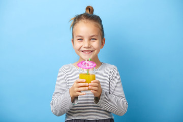 Caucasian child girl drinks orange juice and smiling.