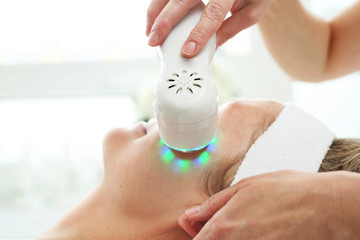 Ultrasonic facial massage using light therapy. Professional treatment in a cosmetics clinic.