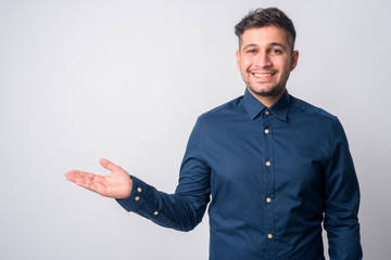 Portrait of happy young handsome Persian businessman showing something