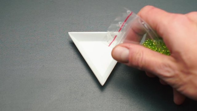 Pouring green beads into a triangular plate