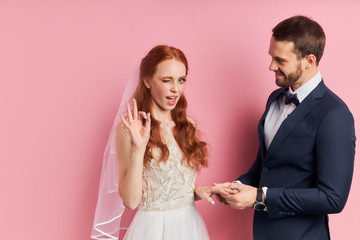 Joyful cheerful bride in white wedding dress and veil on head emotionally responds to a marriage...