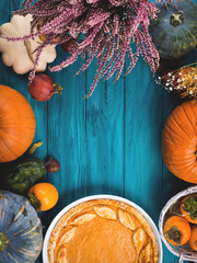 Autumn thanksgiving moody background with pumpkin pie, different pumpkins, fall fruit and flowers on green rustic wooden table. Flat lay - 300315920