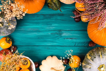 Autumn thanksgiving moody background with different pumpkins, fall fruit and flowers on rustic wooden table. Flat lay