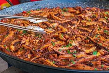 Background with fillets of octopus in a big pan