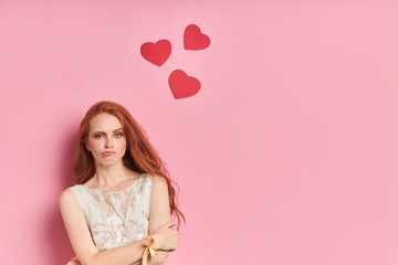 Frustrated woman with auburn hair stand stand looking at camera isolated over pink background. Peple concept