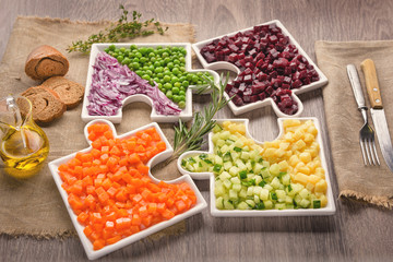 Diced vegetables for salad. Healthy food. Delicious fresh pieces of vegetables of carrots, cucumber, potatoes, beets and peas close-up with fresh onion and olive oil bag cloth on rustic gray table.