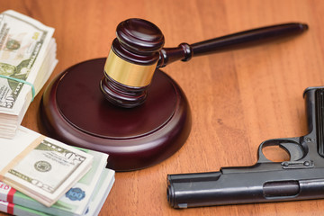 Trial for robbery with murder. Murder and robbery of businessman and the court. Money, gun and judge's gavel on the table.