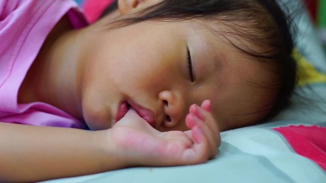 Sleeping Asian little cute baby sucking thumb.