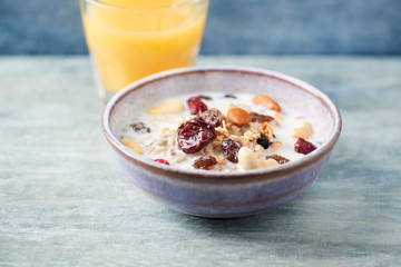 Bowl of granola with milk, nuts, raisins and cranberries. Concept for a tasty and healthy meal. Rustic wooden background. Close up.
