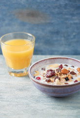 Bowl of granola with milk, nuts, raisins and cranberries. Concept for a tasty and healthy meal. Rustic wooden background. Close up.