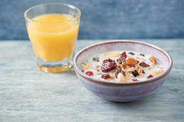 Bowl of granola with milk, nuts, raisins and cranberries. Concept for a tasty and healthy meal. Rustic wooden background. Close up.