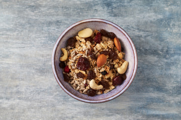 Bowl of granola with nuts and raisins. Concept for a tasty and healthy meal. Rustic wooden background. Top view. Copy space. 