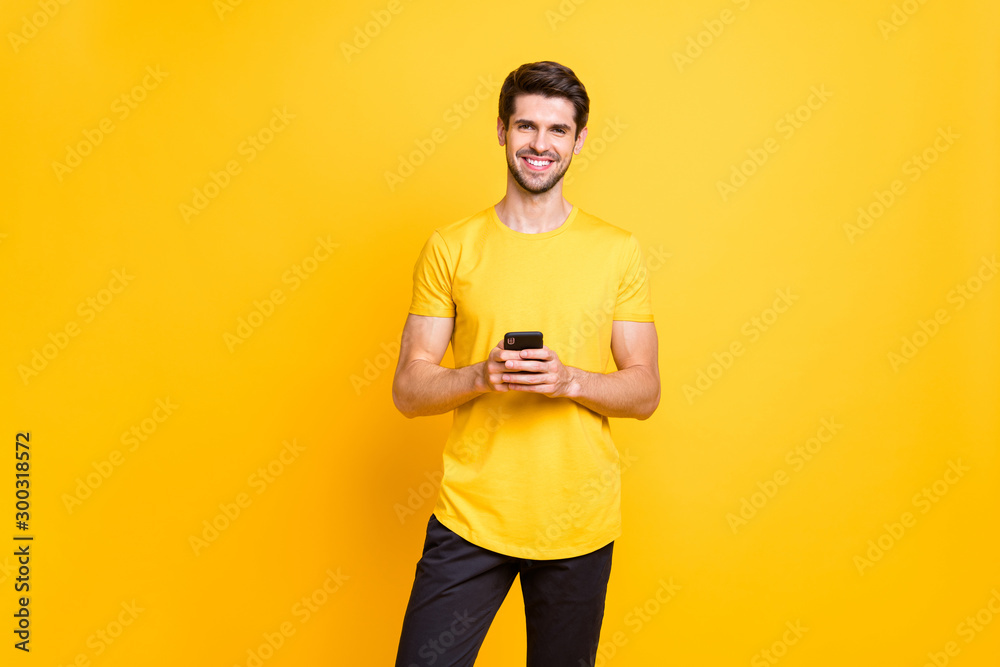 Wall mural photo of toothy cheerful cute attractive handsome man influencing people via his telephone by postin