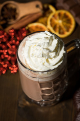 Heiße, dunkle Trinkschokolade zu Weihnachten mit Sahne, Lebkuchen, Schokoladentafel, Gewürzen, Glitzer Schneeflocken rot auf dunkel Holz Hintergrund 