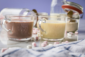 Zubereitung von heißer, dunkle und weiße Trinkschokolade mit Milch, Kakaopulver und Marshmellows auf Marmor hell Hintergrund 