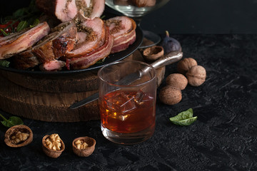 A glass of whisky or brandy with a pork ham stuffed with walnuts and spinach wrapped in bacon. Meatloaf with nuts and herbs. Festive cuisine. - 300319159