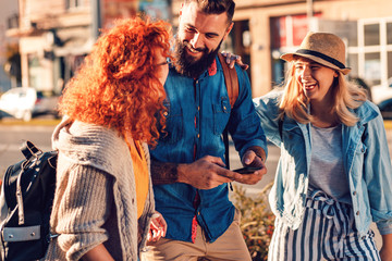 Group of tourists enjoying on vacation, young friends having fun walking on city street during the day.