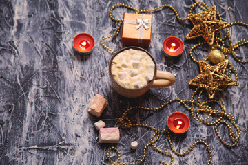 cup of coffee with marshmallows on a table with candles and christmas stuff
