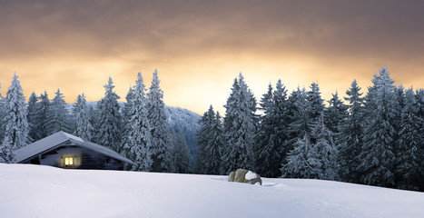 Blockhaus mit beleuchtetem Fenster in Winterwald bei Nacht