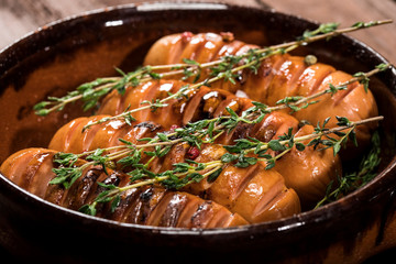 Sausages with thyme in a pan on wooden background.