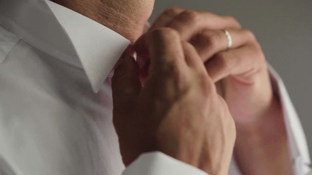 Sposo mentre si abbottona il colletto della camicia nella sua camera da letto