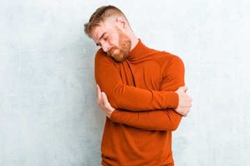 young red head man wearing turtle neck feeling in love, smiling, cuddling and hugging self, staying...